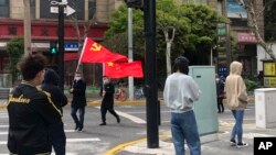 上海静安区居民排队做新冠病毒核酸检测，路上有人打着中共与中国的旗帜走过。（2022年4月1日）