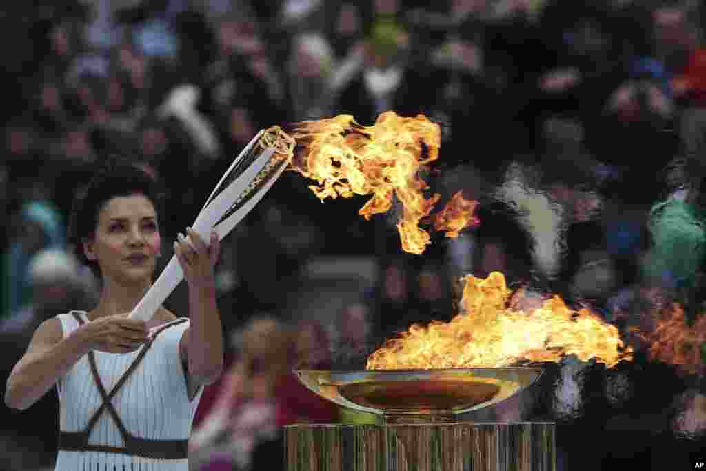 Actress Katerina Lehou playing the role of high priestess lights an Olympic torch during a handover ceremony for the Olympic Flame at Panathenaic stadium in Athens, Greece,