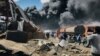 FILE - People are seen in front of clouds of black smoke from fires in the aftermath at the scene of an airstrike in Mekele, the capital of the Tigray region of northern Ethiopia on Oct. 20, 2021.