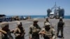 FILE - U.S. soldiers stand at Trident Pier, a temporary pier to deliver aid, off the Gaza Strip, amid the ongoing conflict between Israel and Hamas, near the Gaza coast, June 25, 2024, as an aid truck drives off a ship in the background.