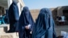 FILE - Afghan burqa-clad women stand in a queue as they wait to receive food being distributed as an aid by the World Food Programme (WFP) organisation at Nawabad Kako Sahib area in Baraki Barak district of Logar Province, Jan. 7, 2024. 