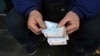 FILE - A street money exchanger counts Iranian banknotes at a commercial district in downtown Tehran, Dec. 23, 2022. 