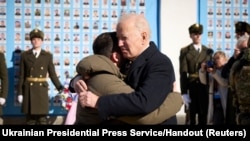 Президент США Джо Байден обіймає президента України Володимира Зеленського на знак підтримки  біля Стіни пам'яті про загиблих українських солдатів в час російського вторгнення в Україну. 20 лютого 2023 року. 