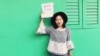 FILE - In this photo released by #FreeXueBing, Chinese journalist Huang Xueqin holds up a #METOO sign for a photo in Singapore in September 2017.