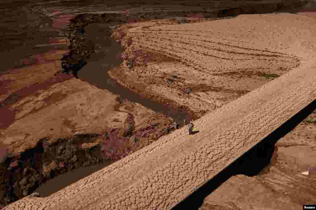 A man walks on the cracked ground of the Baells reservoir as drinking water supplies have plunged to their lowest level due to extreme drought in Catalonia, in the village of Cersc, in the region Bergueda, Spain, March 14, 2023. 