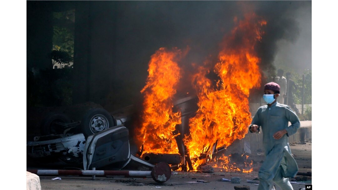 FILE - A man runs past a burning car set on fire by angry supporters of Pakistan's former Prime Minister Imran Khan during a protest against the arrest of their leader, in Peshawar, Pakistan, May 10, 2023.