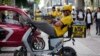 A delivery rider checks his phone as he rests on his bike outside a shopping mall in Beijing, Aug. 15, 2023. Amid high youth unemployment, some Chinese are trying to find opportunities in such sectors as food delivery and livestreaming.