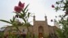 This picture taken on July 19, 2023 shows people passing an old disused mosque in Artux, northwestern China's Xinjiang region. 