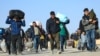 FILE - Afghan immigrants deporting back from Iran, carry their belongings at a registration center in the Islam Qala border town of Herat province on Nov. 6, 2023.