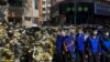Security personnel in blue vests stand guard in front of the flowers laid by residents near a residential building where the late Chinese Premier Li Keqiang spent his childhood in Hefei city, in central China's Anhui province, Nov. 2, 2023. 