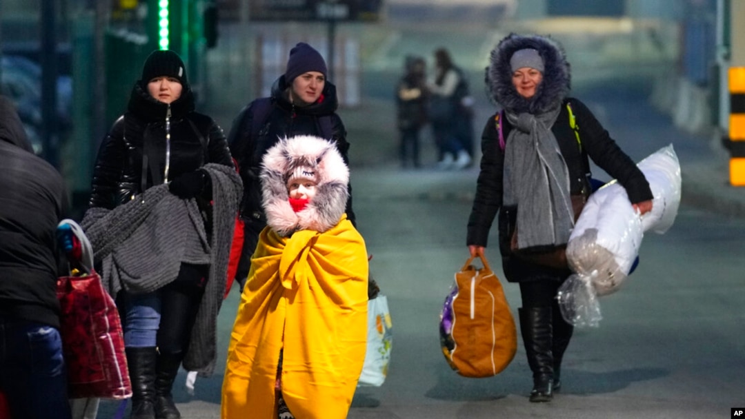 FILE - People fleeing the conflict in neighboring Ukraine cross the border in Przemysl, Poland, Feb. 27, 2022. 