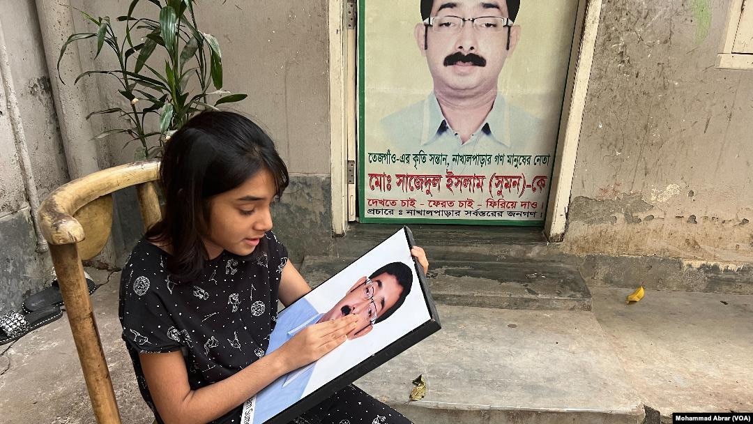 Arowa Islam, 11, sits with the photo of her father, opposition Bangladesh Nationalist Party leader Sajedul Islam Shuman, August 16, 2022. Shuman remains missing after RAB allegedly abducted him from Dhaka in 2013. (Photo by Mohammad Abrar for VOA)