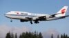 The Air China Boeing 747-400 plane carrying Chinese President Xi Jinping flies over a line of evergreen trees as it heads in to land, Sept. 22, 2015, at Boeing Field in Everett, Wash. 