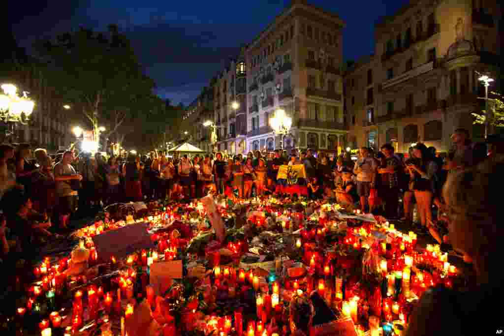 People gather at a memorial tribute of flowers, messages and candles to the victims on Barcelona&#39;s historic Las Ramblas promenade where the van stopped after killing at least 13 people in Barcelona , Spain.
