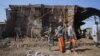 FILE - Residents and militia members stand next to houses destroyed by an airstrike during the fight between the Ethiopian National Defense Forces and the Tigray People's Liberation Front forces in Kasagita town, Afar region, Ethiopia, Feb. 25, 2022.