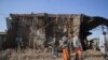FILE - Residents and militia members stand next to houses destroyed by an airstrike during the fight between the Ethiopian National Defense Forces and the Tigray People's Liberation Front forces in Kasagita town, Afar region, Ethiopia, Feb. 25, 2022.