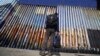 FILE - A migrant waits on the Mexican side of the border after U.S. Customs and Border Protection officers detained a couple of migrants crossing the U.S.-Mexico border on the beach, in Tijuana, Mexico, Jan. 26, 2022.
