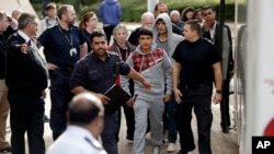 FILE - Two unidentified young migrants get off a bus as they arrive at Lunar House, which houses the headquarters of UK Visas and Immigration in Croydon, south London, Monday, Oct. 17, 2016. 