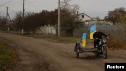 Учитель Юрій Невольчук їде на мотоциклі з українськими прапорами в селі Благодатне, відвойованому ЗСУ на Херсонщині, 11 листопада 2022 року. REUTERS/Валентин Огіренко