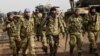 Syrian opposition fighters backed by Turkey walk in front of Turkish troops near the Syria border at Hassa, Hatay province on Jan. 22, 2018. 