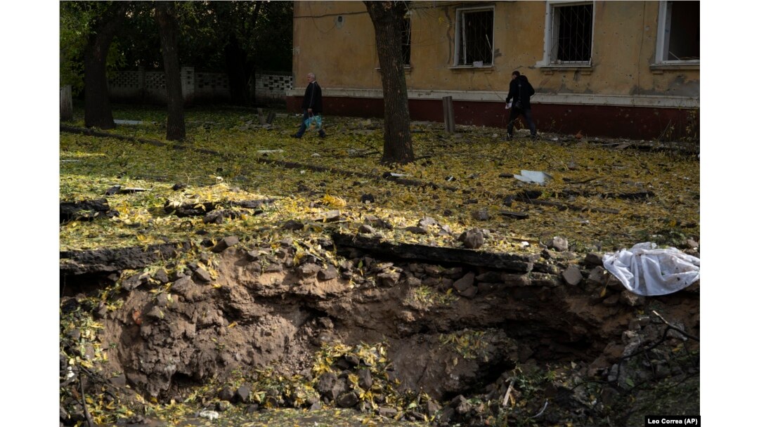 People walk past a crater created by an explosion after a Russian attack in Kramatorsk, Ukraine, Thursday, Sept. 29, 2022 (AP Photo/Leo Correa)