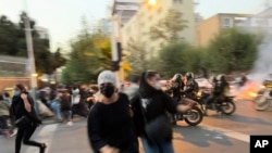 FILE - In this Sept. 19, 2022, photo taken by an individual not employed by the Associated Press and obtained by the AP outside Iran, women run away from anti-riot police during an anti-government protest in downtown Tehran.