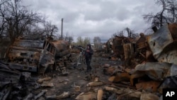 Чоловік везе велосипед вулицею, наповненою знищеною російською військовою технікою, поблизу Чернігова, Україна, неділя, 17 квітня 2022 року. (AP Photo/Євген Малолетка)