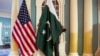 A State Department employee adjusts a Pakistani national flag before a meeting of U.S. and Pakistani officials at the State Department in Washington, Feb. 19, 2015. A U.S. Defense Department delegation is traveling to Pakistan for talks next week. 