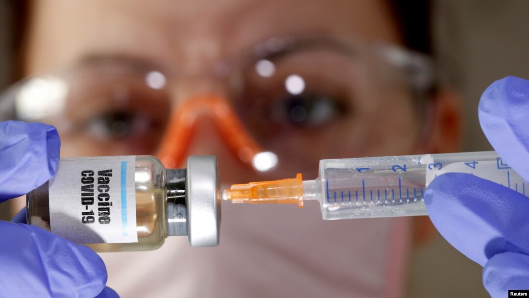 FILE - A woman holds a small bottle labeled "Vaccine COVID-19" and a medical syringe in this illustration taken April 10, 2020. 