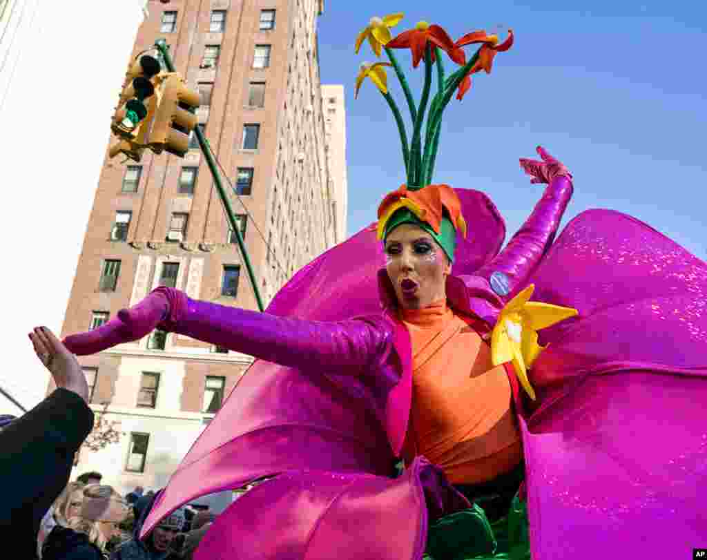 A participant in the Macy&#39;s Thanksgiving Day Parade touches hands with a spectator along Central Park West in New York.