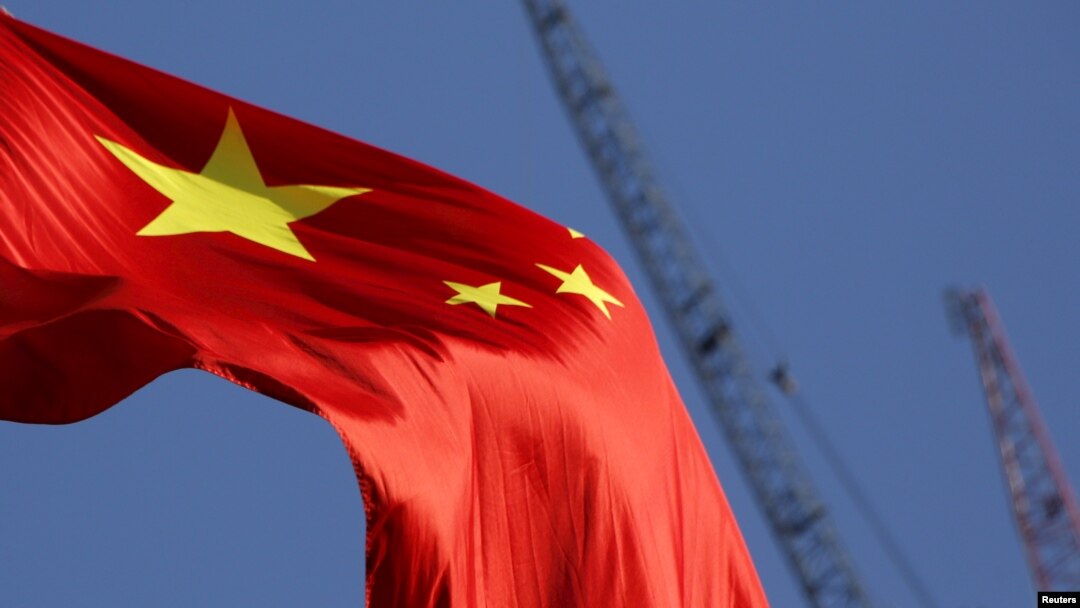 China's national flag is seen in front of cranes on a construction site at a commercial district in Beijing, China, Jan. 26, 2016. 