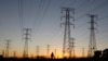 FILE - A man walks past electricity pylons as he returns from work in Soweto, outside Johannesburg.