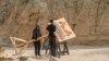 Production crews remove a sign after dangerously high winds forced President Joe Biden to cancel a trip Jan. 7, 2025, to the Eastern Coachella Valley, California, where he was to announce the creation of two new national monuments in California.