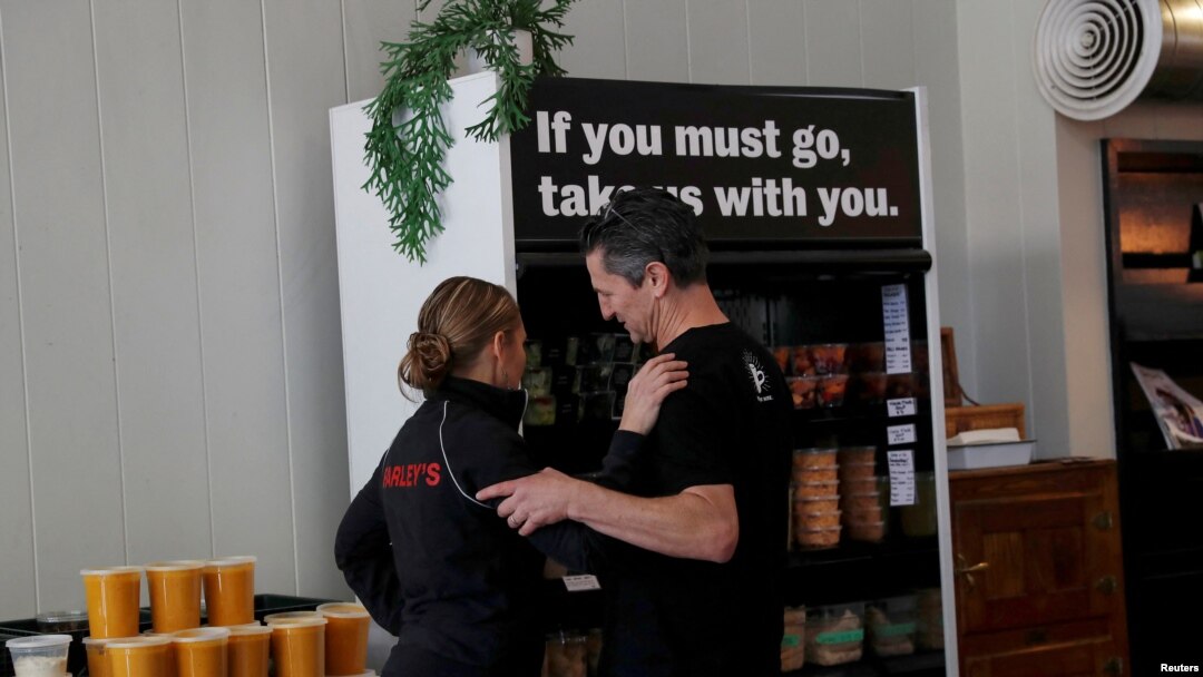 Amy and Chris Hillyard, owners of Farley's East cafe that closed due to the financial crisis caused by COVID-19, embrace at the cafe in Oakland, Calif., March 18, 2020.