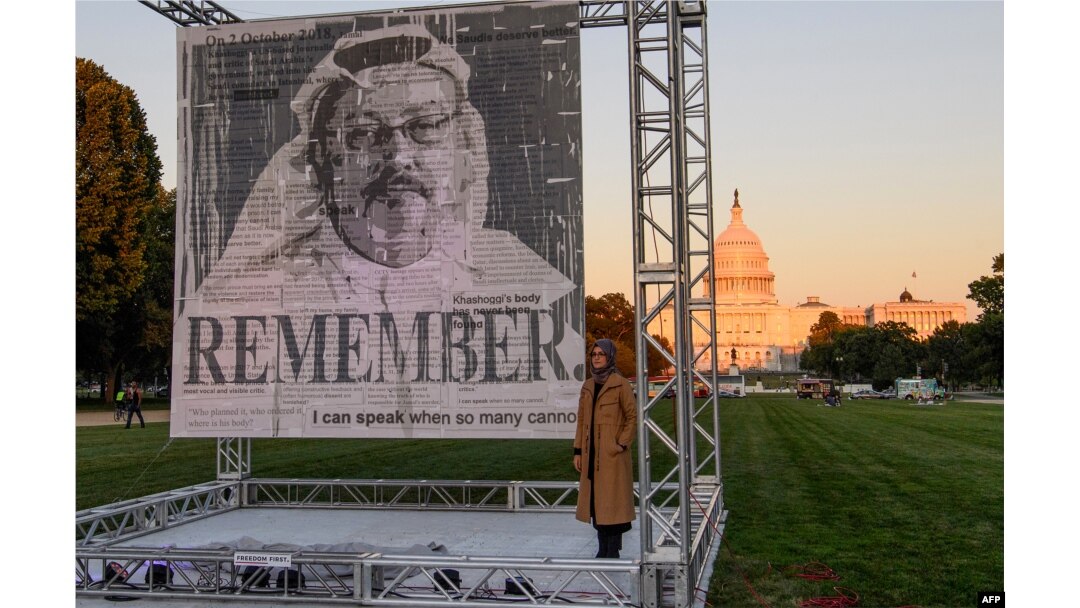 FILE - Turkish writer Hatice Cengiz, right, fiancée of Saudi journalist and dissident Jamal Khashoggi, poses next to a portrait of Khashoggi after unveiling it on the National Mall in Washington, Oct. 1, 2021