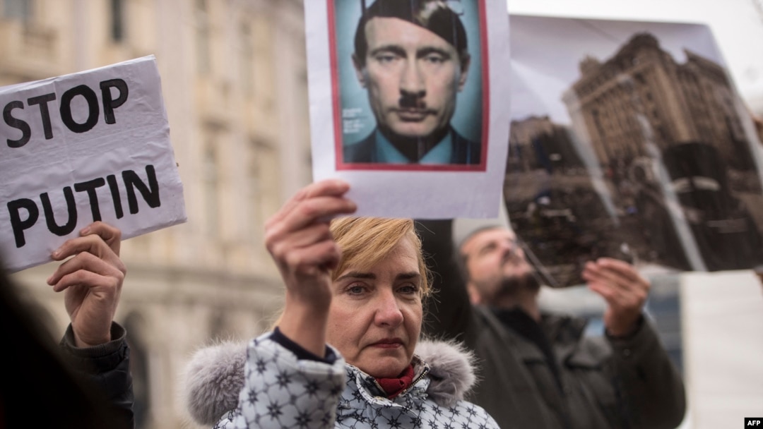 FILE - A protester holds a photo depicting Russian President Vladimir Putin as Adolf Hitler during a demonstration against Russia's invasion of the Ukraine, in Skopje, North Macedonia, March 6, 2022.