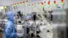 FILE - Employees wearing protective equipment work at a semiconductor production facility for Renesas Electronics during a government organized tour for journalists in Beijing, on May 14, 2020. 