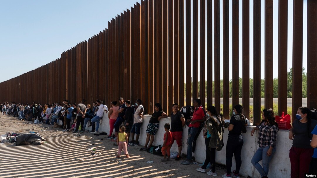 FILE - Asylum-seeking migrants, mostly from Venezuela and Cuba, wait to be transported by U.S. Customs and Border Protection agents after crossing the Rio Grande River into the U.S. from Mexico at Eagle Pass, Texas, July 14, 2022. 
