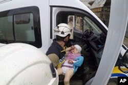 This photo provided by the Syrian Defense White Helmets shows a civil defense worker carrying a child after shelling hit a street in the town of Nairab, in the eastern province of Idlib, Syria, Apr. 7, 2019.