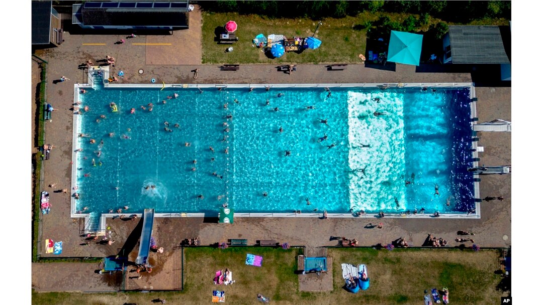 People spend time in a public pool in Wehrheim near Frankfurt, Germany, on a hot Saturday, July 8, 2023. (AP Photo/Michael Probst)