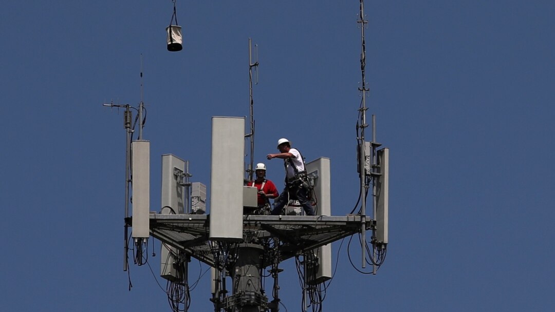 Workers install 5G telecommunications equipment on a T-Mobile tower in Seabrook, Texas, May 6, 2020.