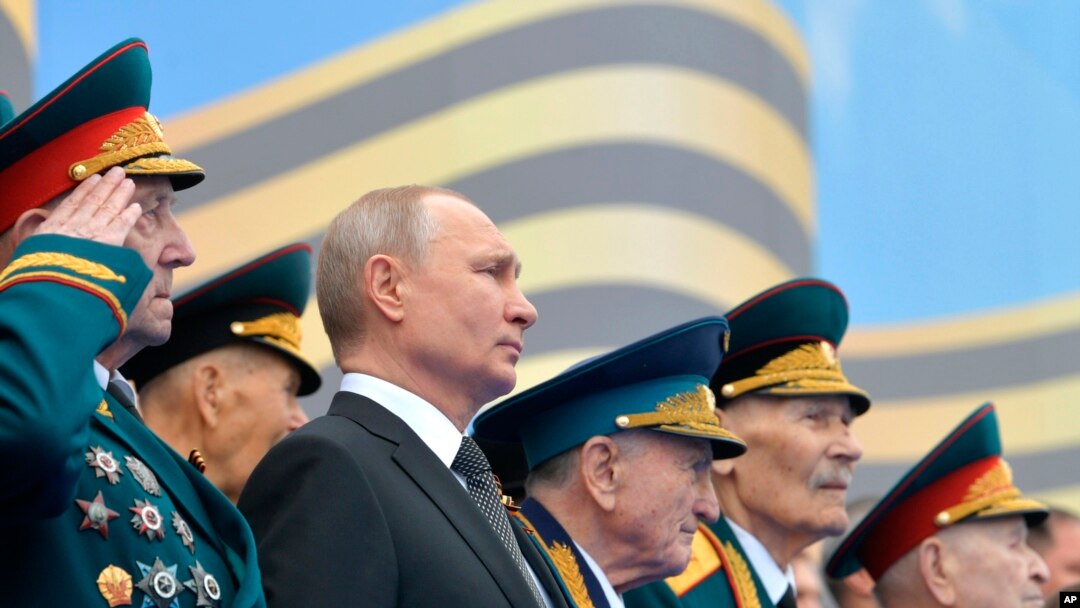 FILE - Flanked by World War II veterans, Russian President Vladimir Putin watches a military parade marking 74 years since the end of World War II, in Red Square, in Moscow, Russia, May 9, 2019.