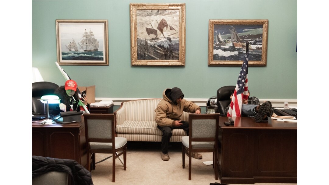 FILE - Supporters of U.S. President Donald Trump sit inside the office of U.S. Speaker of the House Nancy Pelosi as they protest inside the U.S. Capitol in Washington, Jan. 6, 2021.