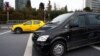 FILE - An Uber driver drives his car with a taxi seen in the background, in Istanbul, Turkey, March 15, 2018.
