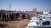 Les résidents du quartier informel de Nomzamo réagissent à une scène de crime où 14 personnes ont été abattues dans une taverne à Soweto le 10 juillet 2022.