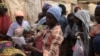 Blessing John, who escaped from Boko Haram, hands out used clothes to internally displaced people at the Sabon Kuchigora refugee settlement on the outskirts of Abuja, Dec. 17. (Chris Stein/VOA)