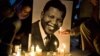 People light up candles in front of a photo of former South African president Nelson Mandela, at the Trocadero Square, in Paris, Sunday, Dec. 15, 2013.