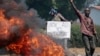 An opposition demonstrator holds a sign in French reading "No to a third term" next to a barricade fire set by protesters in the Ngagara neighborhood of Bujumbura, Burundi, June 3, 2015.