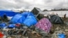 FILE - Migrants walk among tents in a muddy field at the Jungle near Calais, France, Feb. 3, 2016. 