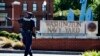 An armed officer who said he is with the Department of Defense, warns a vehicle to stay away from the gate at the Washington Navy Yard, closed to all but essential personnel, in Washington, on, Sept. 17, 2013/
